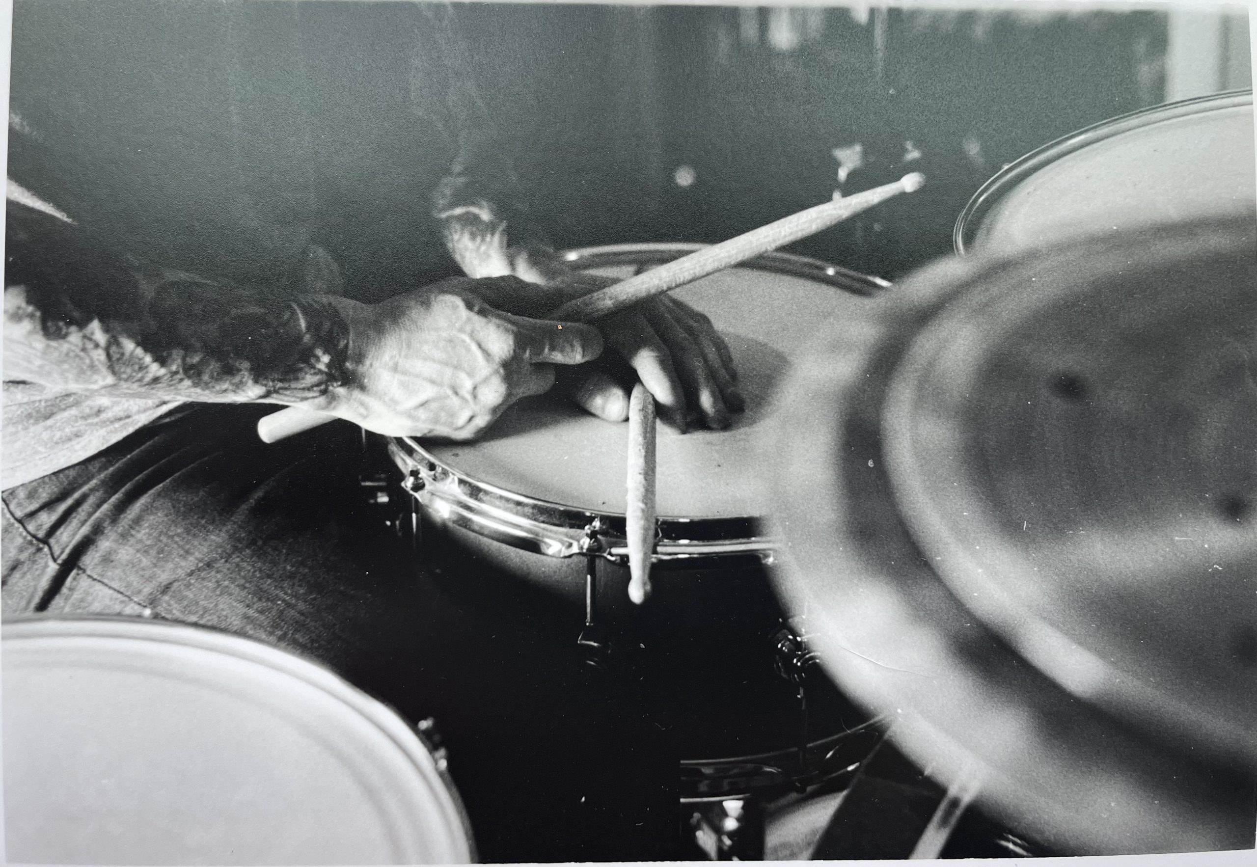 hand holding drumsticks resting on snare drum